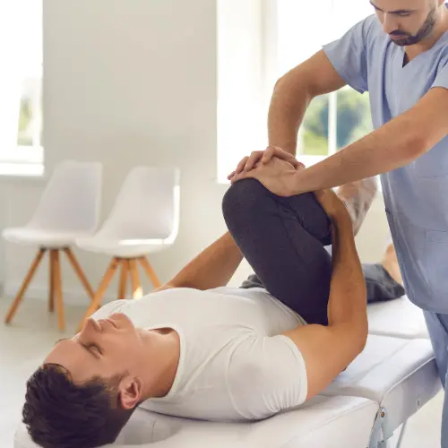 Fizioterapevt izvaja rehabilitacijo kolka pri pacientu za zmanjšanje bolečine.